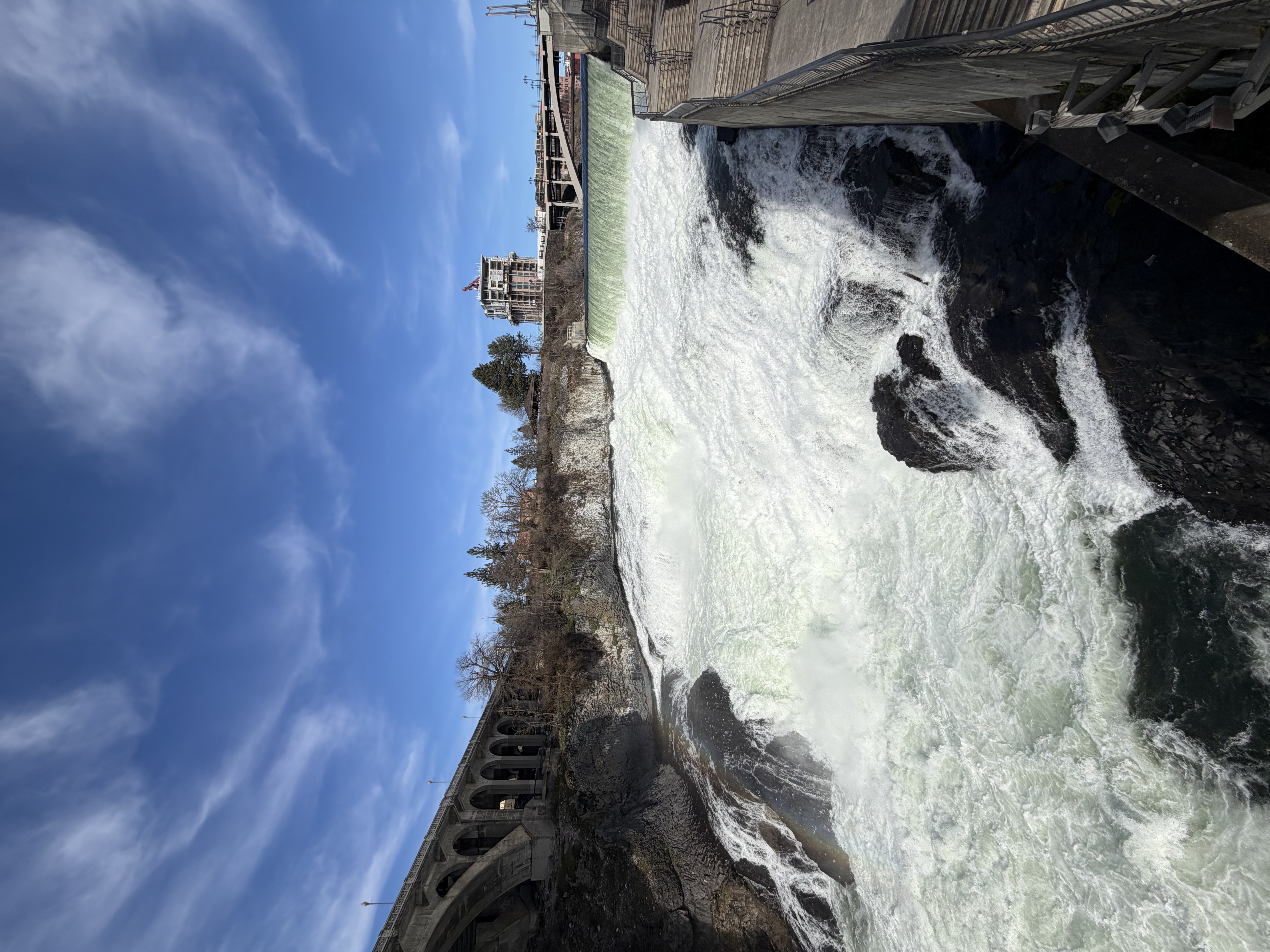 Spokane Falls rushing beneath a bright blue sky