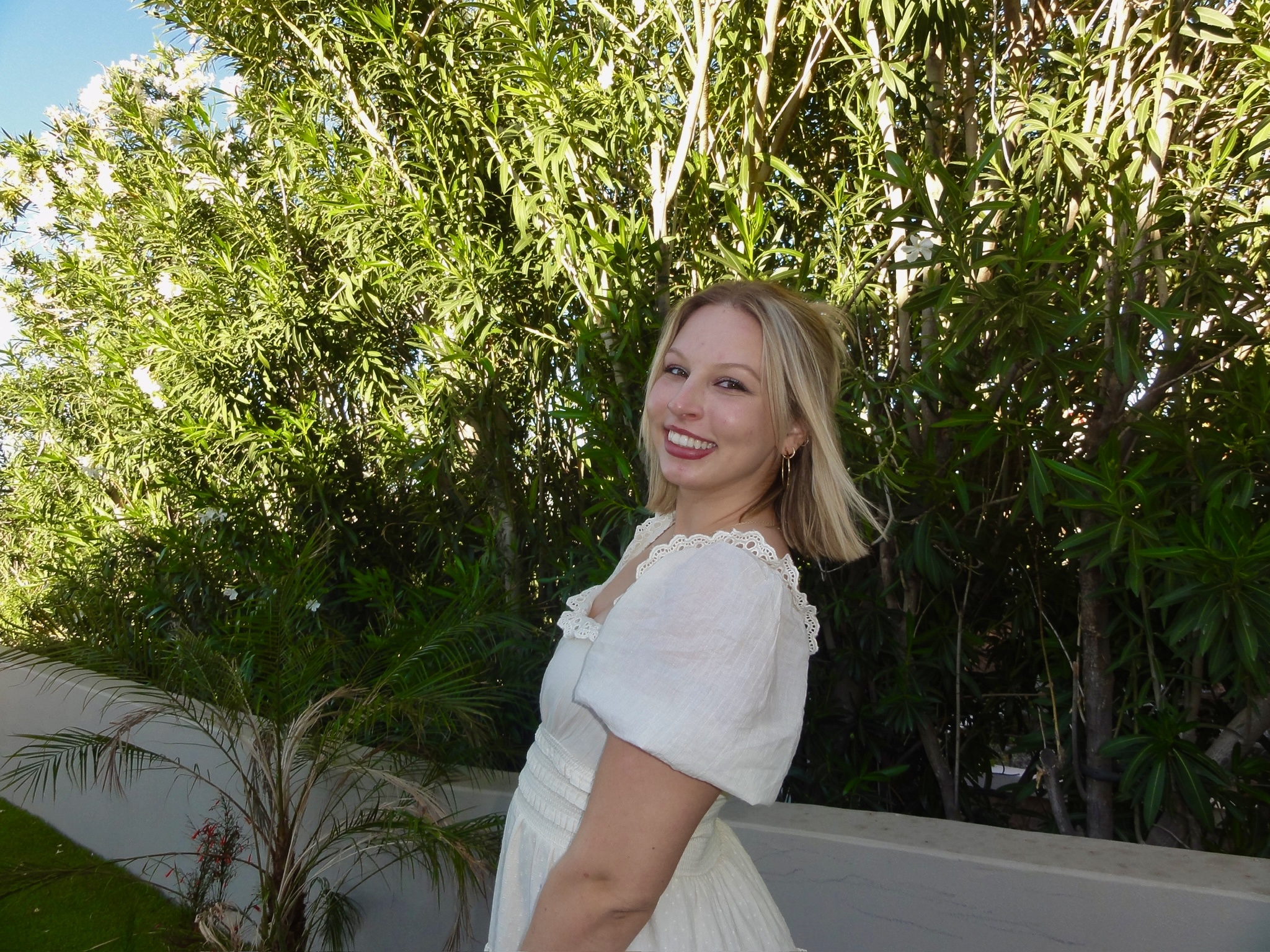 Natalie, founder of Nat's Crafts Co, standing outdoors in a white dress